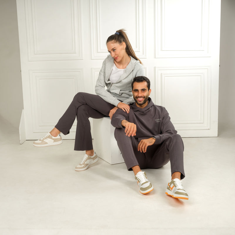 People in casual outfits wearing stylish Alexis sneakers in beige and white, sitting and posing in a minimalistic room.