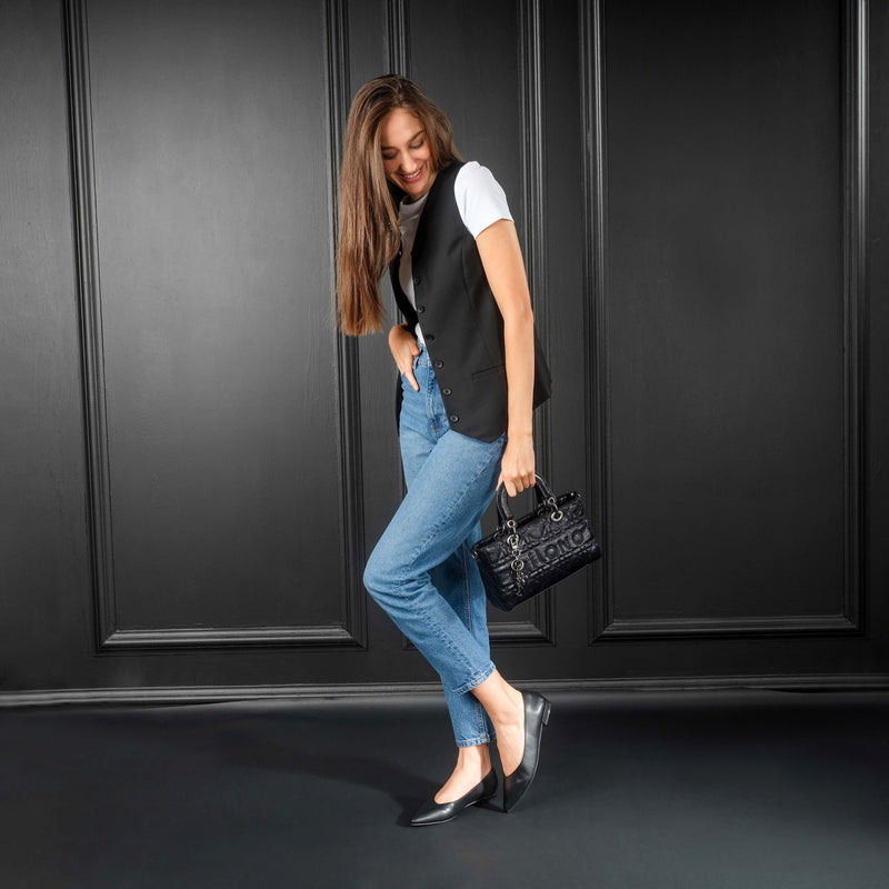 Woman wearing stylish Kiril pump flat in black, paired with jeans and vest, showcasing a versatile and minimalist shoe design.